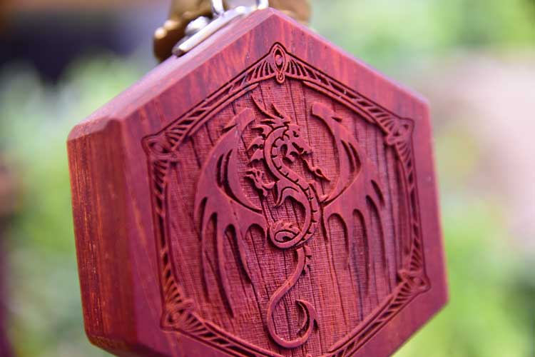 A red padauk mini hex chest, showing the detail of the dragon engraving on the wood