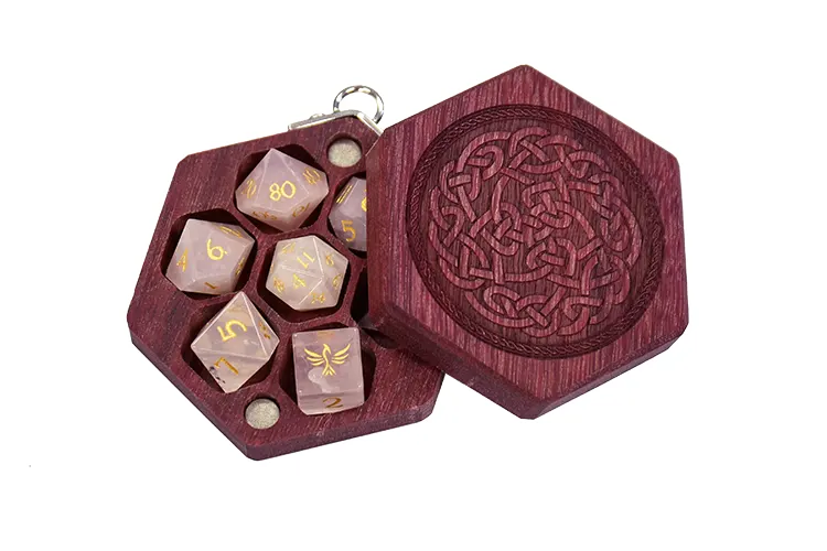 A purpleheart wood Mini Hex Chest dice box with a Celtic knot engraving and pink rose quartz mini polyhedral dice for tabletop gaming