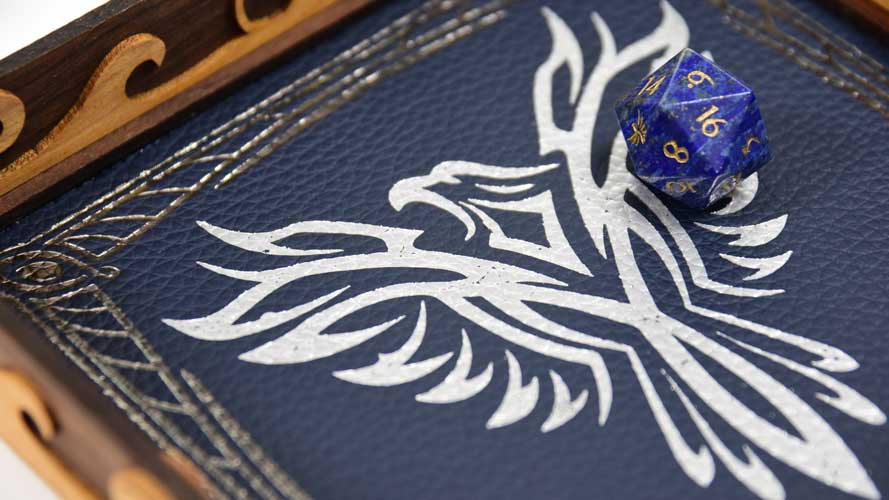 Close-up shot of a scroll rolling tray's foil-pressed blue leather with a D20 die for dungeons and dragons